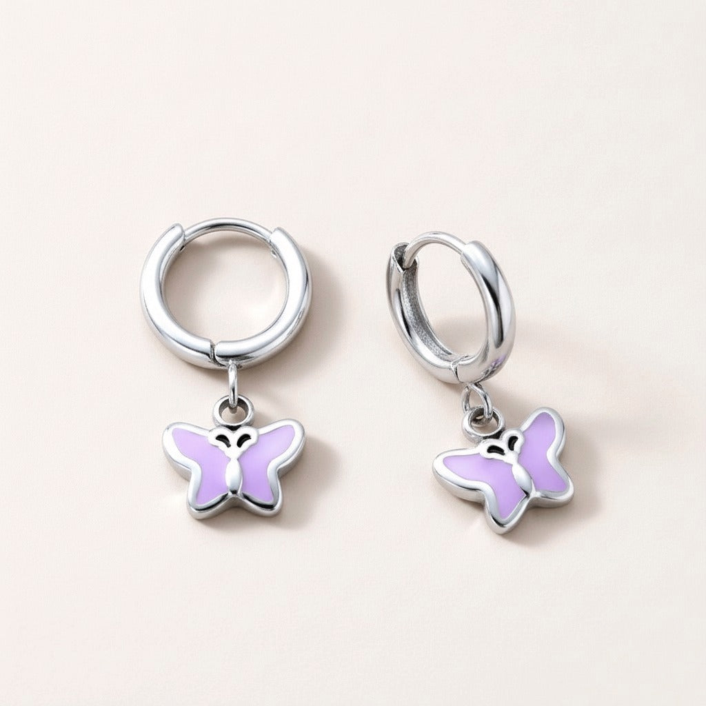 Butterfly Flutter Huggies Silver: hypoallergenic kids' huggie hoop earrings, shown front and side on a soft stone background