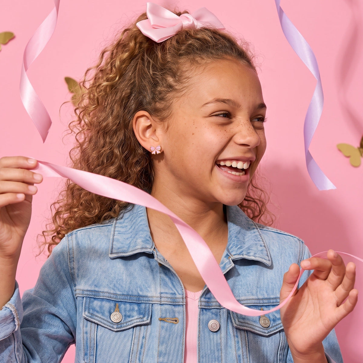 Candy Bow Flat Back Studs worn by a smiling girl, bows butterflies look: hypoallergenic kids' earrings