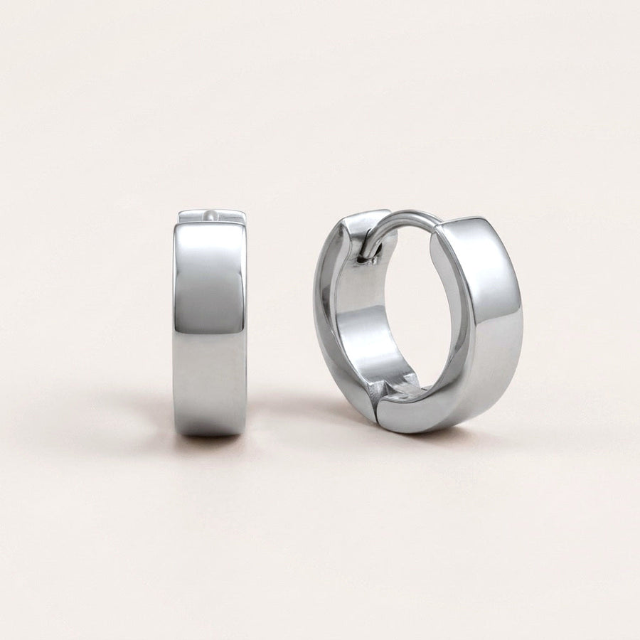 Classic Bold Huggies Silver: hypoallergenic huggie hoop earrings, shown front and side on a soft stone background