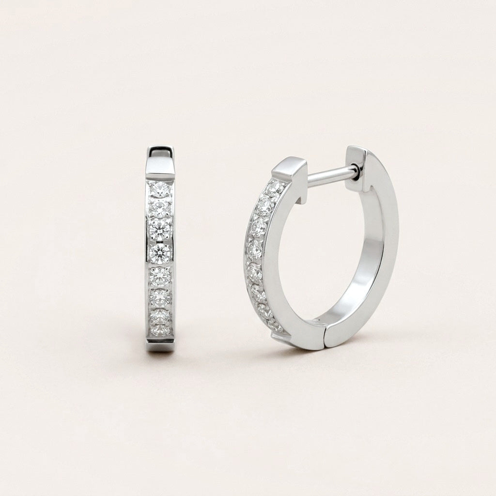 Everyday Sparkle Huggies Silver: hypoallergenic huggie hoop earrings, shown front and side on a soft stone background