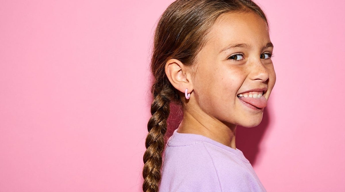Girl with a braid pulling a cheeky face, wearing pink hoop earrings