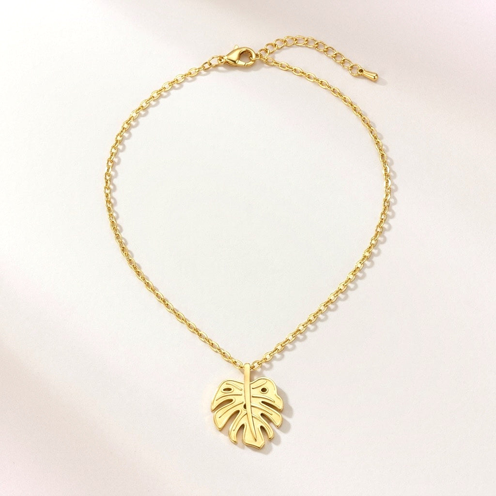 Golden Monstera Necklace: hypoallergenic necklace, shown front and side on a soft stone background