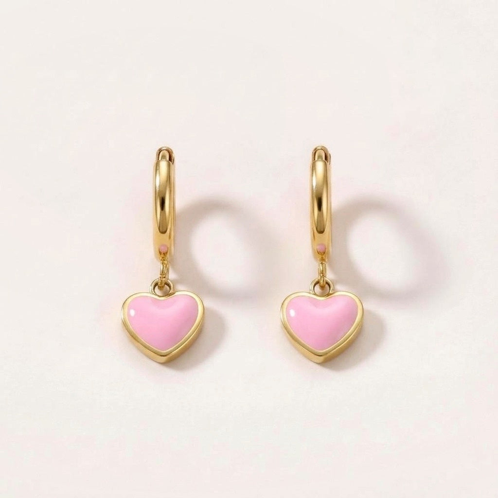 Heart Huggies Gold in Pink: hypoallergenic kids' huggie hoop earrings, shown front and side on a soft stone background