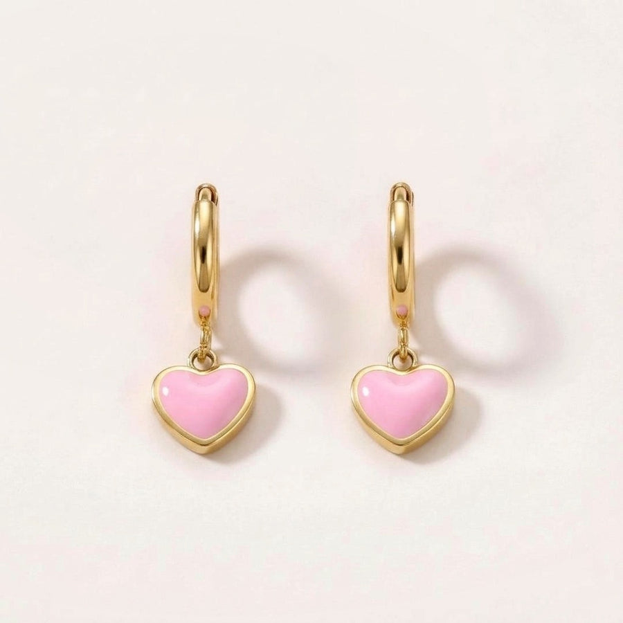 Heart Huggies Gold in Pink: hypoallergenic kids' huggie hoop earrings, shown front and side on a soft stone background