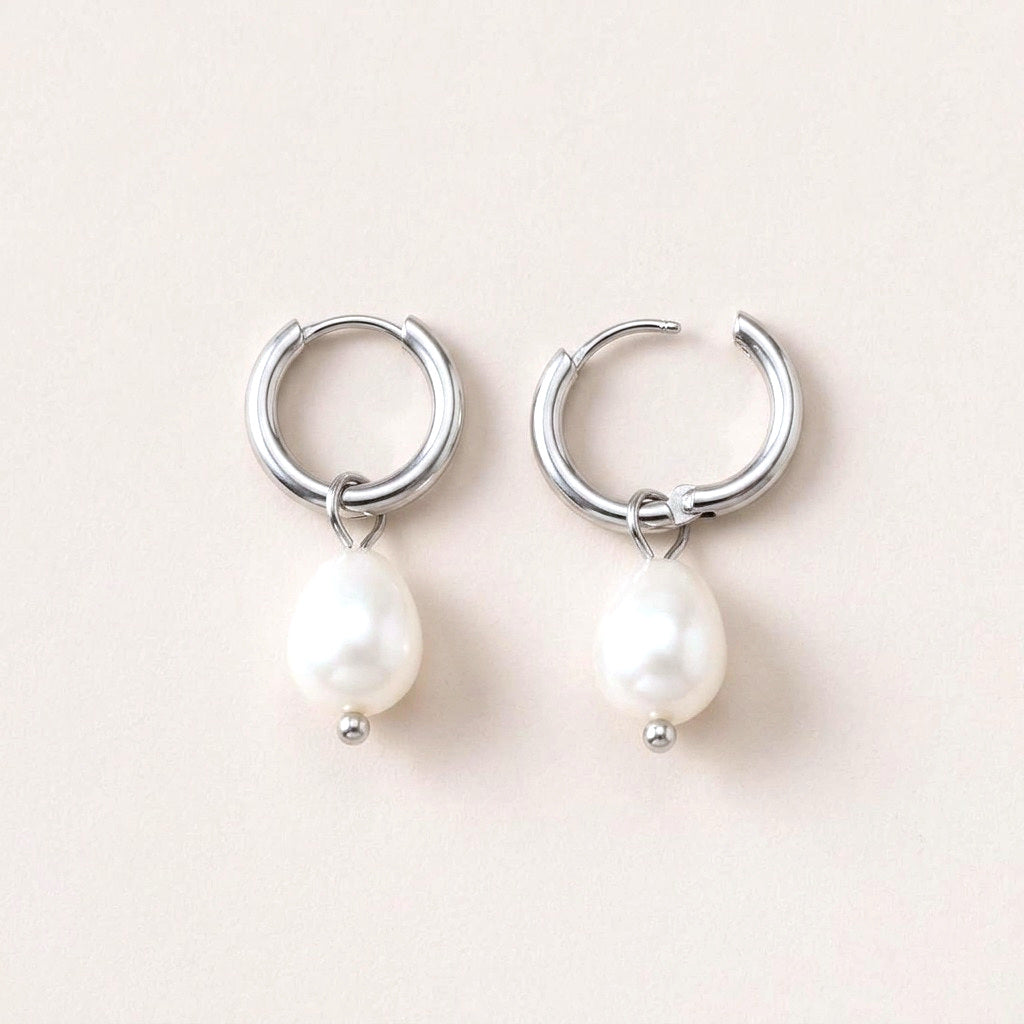 Luna Pearl Drop Huggies Silver: hypoallergenic huggie hoop earrings, shown front and side on a soft stone background