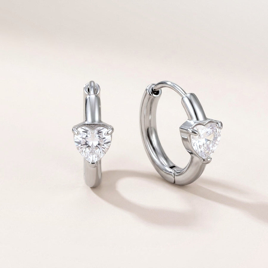 Sweetheart Spark Huggies Silver: hypoallergenic huggie hoop earrings, shown front and side on a soft stone background