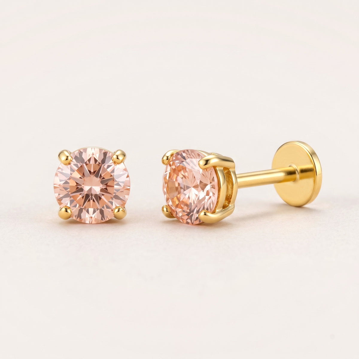 The Birthstone Flat Back Studs Gold in Champagne Pink Ruby: hypoallergenic kids' flat back stud earrings, shown front and side on a soft stone background