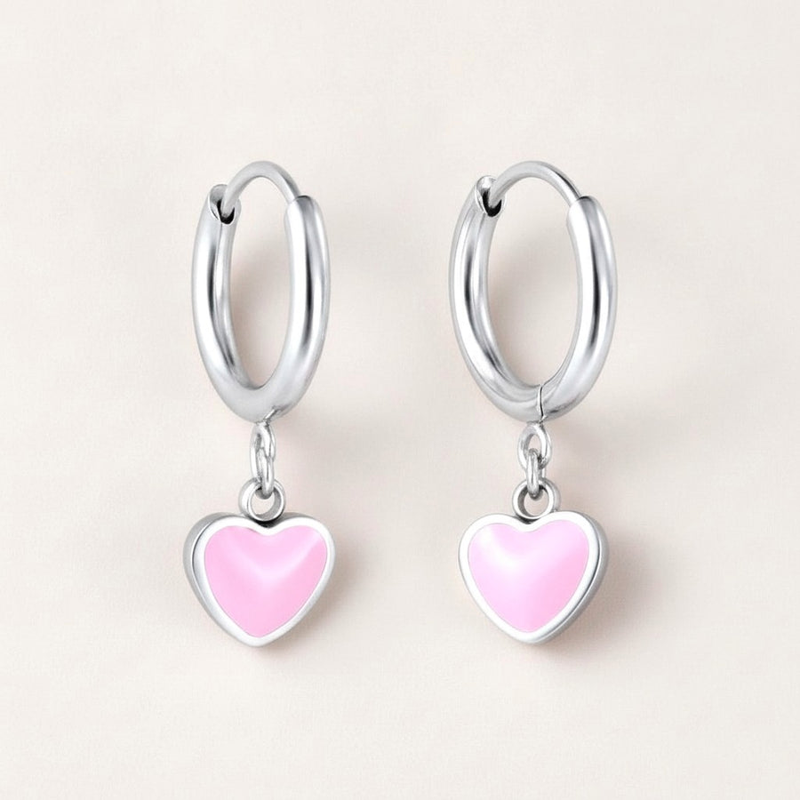 Heart Huggies Silver: hypoallergenic kids' huggie hoop earrings, shown front and side on a soft stone background