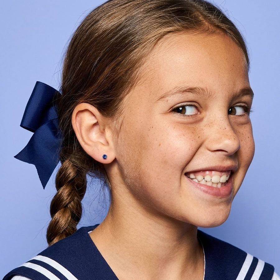 September birthstone earrings: sapphire colour flat back stud worn by a smiling girl