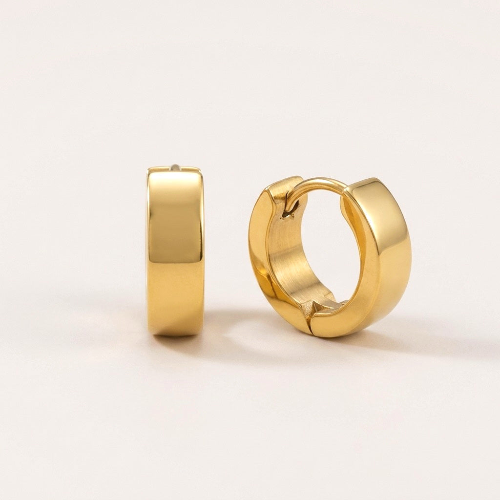Classic Bold Huggies Gold: hypoallergenic huggie hoop earrings, shown front and side on a soft stone background