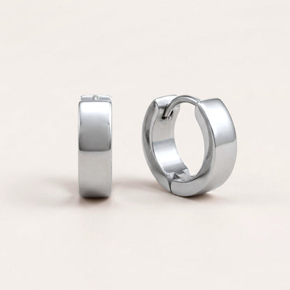 Classic Bold Huggies Silver: hypoallergenic huggie hoop earrings, shown front and side on a soft stone background