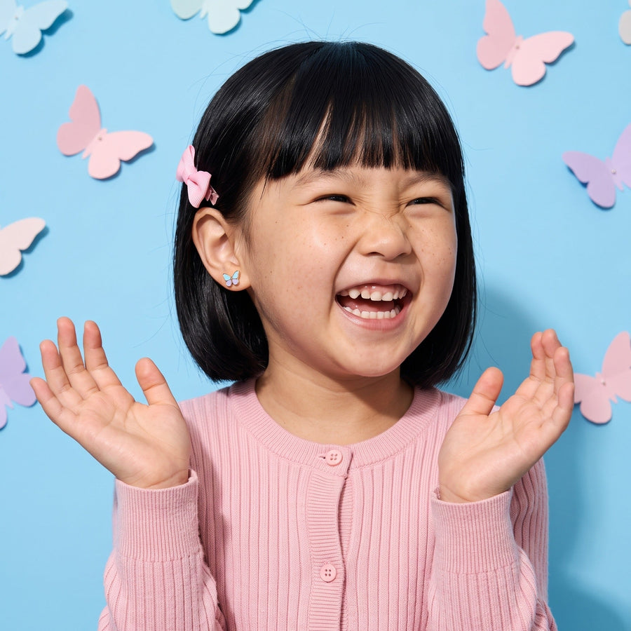 Flutter Flat Back Studs worn by a smiling girl, bows butterflies look: hypoallergenic kids' earrings