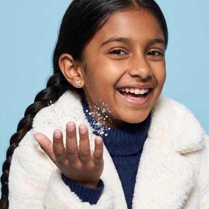 Frosted Bow Flat Back Studs worn by a smiling girl, winter look: hypoallergenic kids' earrings