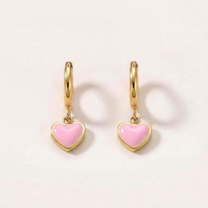 Heart Huggies Gold in Pink: hypoallergenic kids' huggie hoop earrings, shown front and side on a soft stone background