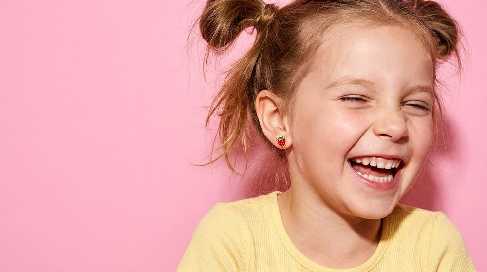 Laughing girl wearing tiny strawberry flat back earrings