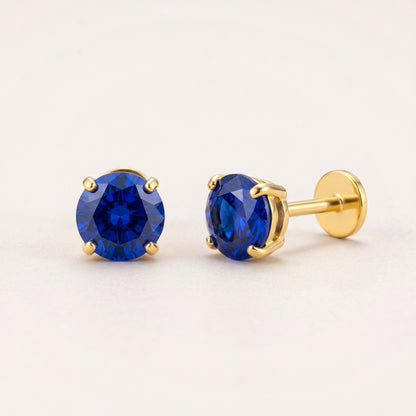 The Birthstone Flat Back Studs Gold in Sapphire: hypoallergenic kids' flat back stud earrings, shown front and side on a soft stone background