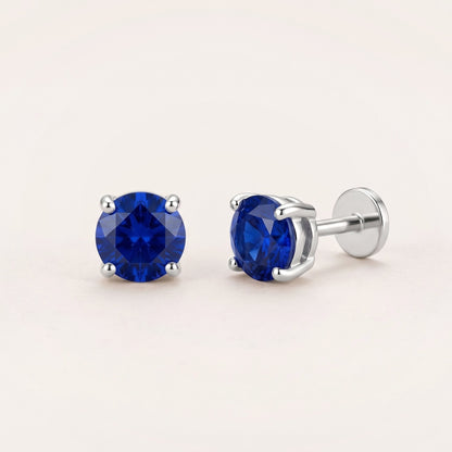 The Birthstone Flat Back Studs Silver in Sapphire: hypoallergenic kids' flat back stud earrings, shown front and side on a soft stone background