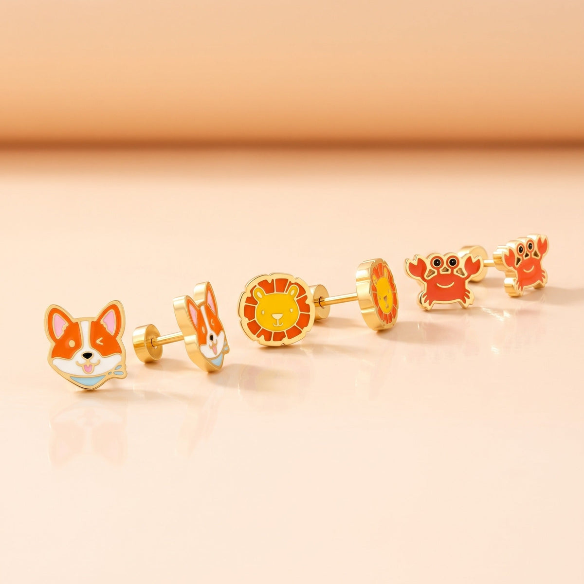 Corgi Flat Back Studs Gold + Little Lion Flat Back Studs Gold + Crabby Flat Back Studs Gold: three hypoallergenic kids' earrings styled together on a soft background