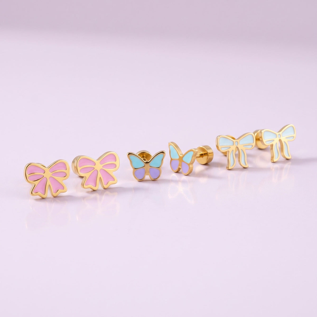 Candy Bow Flat Back Studs + Flutter Flat Back Studs + Frosted Bow Flat Back Studs: three hypoallergenic kids' earrings styled together on a soft background