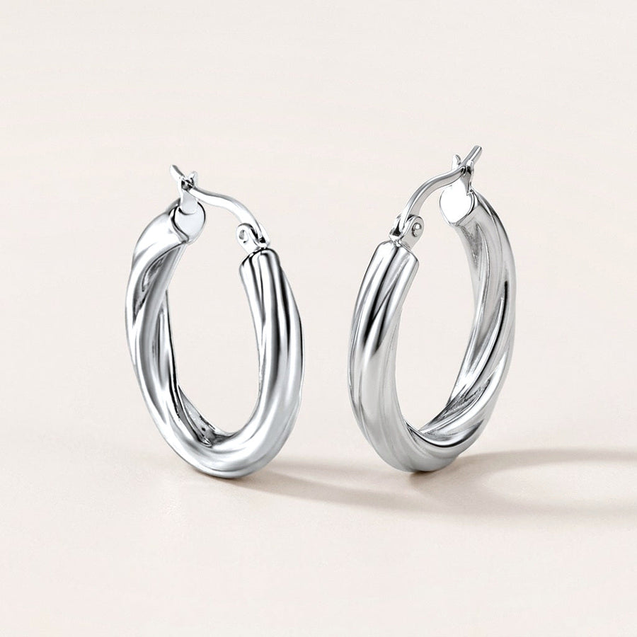 Twisted Hoops Silver: hypoallergenic hoop earrings, shown front and side on a soft stone background