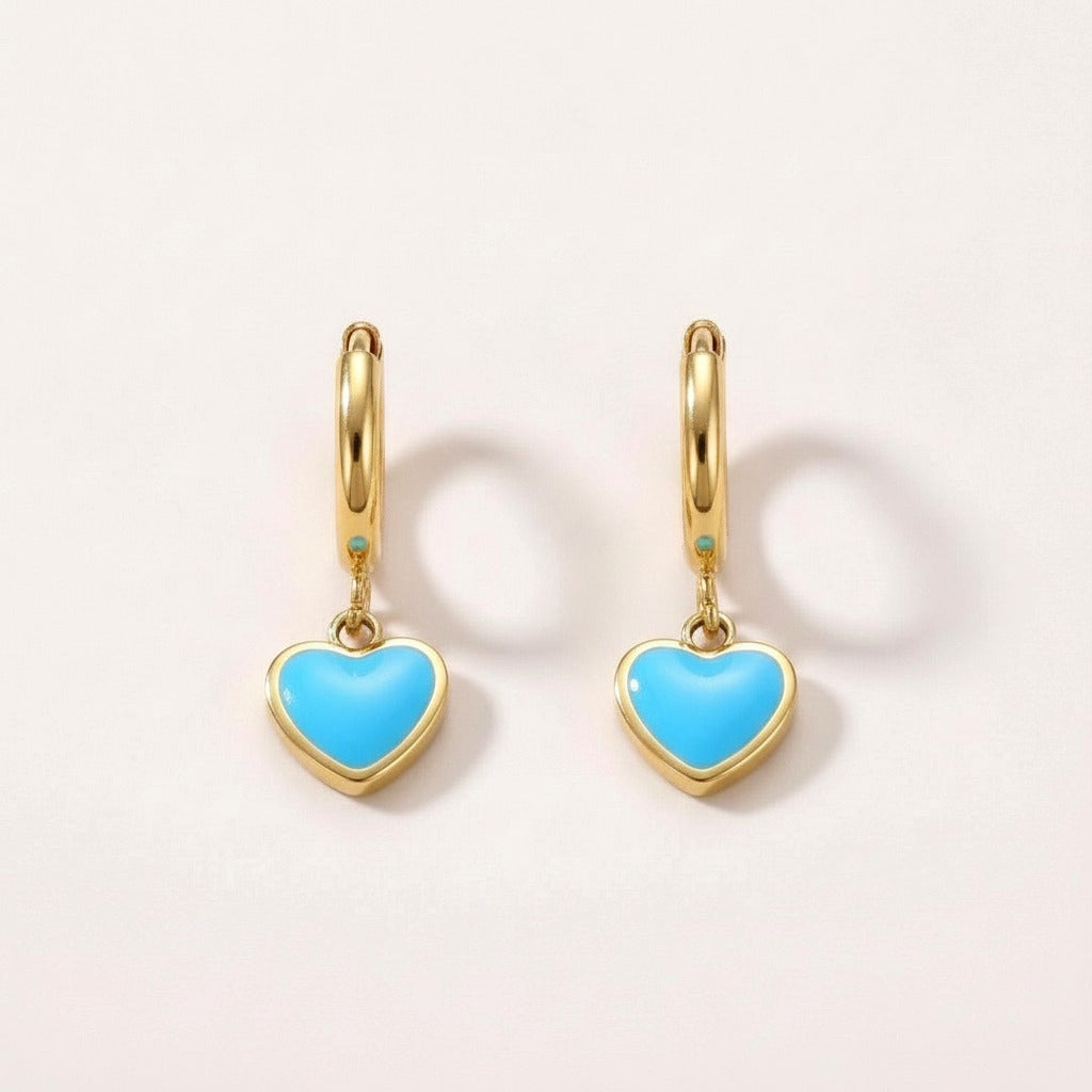 Heart Huggies Gold: hypoallergenic kids' huggie hoop earrings, shown front and side on a soft stone background