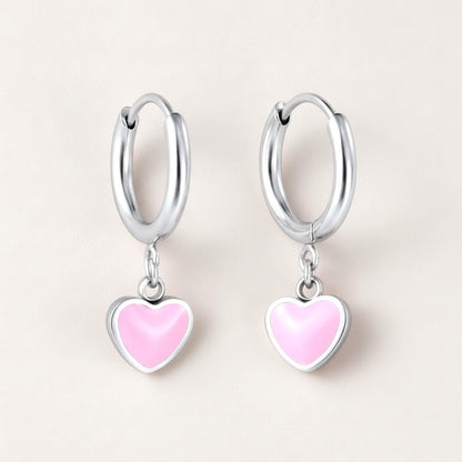 Heart Huggies Silver: hypoallergenic kids' huggie hoop earrings, shown front and side on a soft stone background