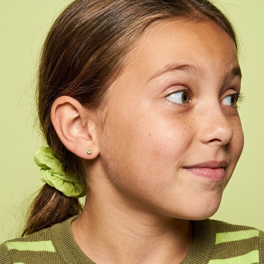 August birthstone earrings: peridot colour flat back stud worn by a smiling girl